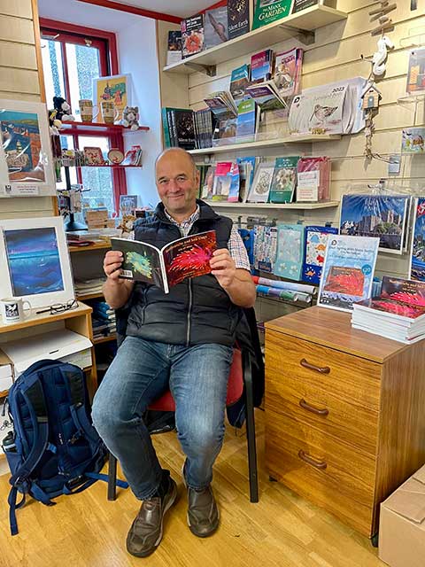 Tim Nicholson holding his nudibranch book in book shop